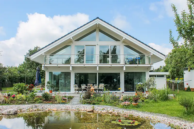 Hintergrund-Bild: Bild eines modernen Fachwerkhauses vor Teichanlage im Grünen